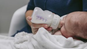 Neonato beve latte in formula che può causare dermatite atopica